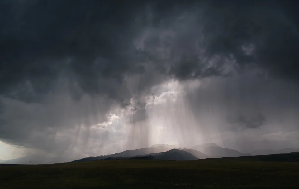 A double rainbow beneath dark thunderstorm clouds
